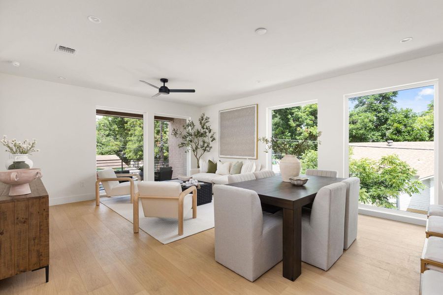 Natural light floods this inviting living and dining space with rich hardwood flooring and a stylish ceiling fan.