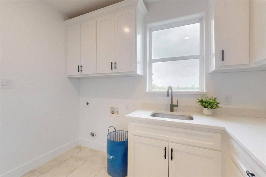 Washroom featuring a sink, hookup for an electric dryer, baseboards, cabinet space, and hookup for a washing machine Washroom featuring a sink, hookup for an electric dryer, baseboards, cabinet space, and hookup for a washing machine