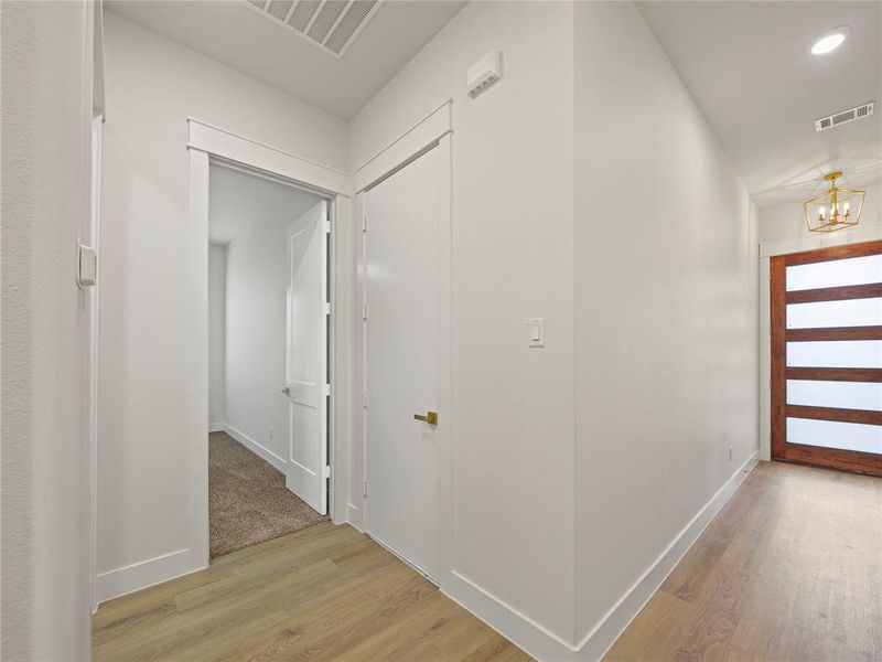 Hallway with light wood-style flooring and a chandelier