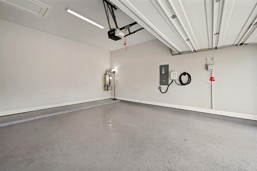 Spacious garage with epoxy-coated flooring, overhead fluorescent lighting, and an automatic garage door opener