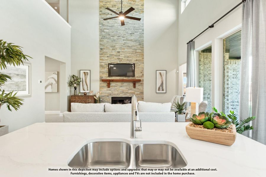 Kitchen island with double sink overlooking open living room with tall stone fireplace and ceiling fan Kitchen island with double sink overlooking open living room with tall stone fireplace and ceiling fan