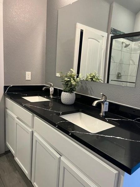 Bathroom with dual vanity and hardwood / wood-style floors
