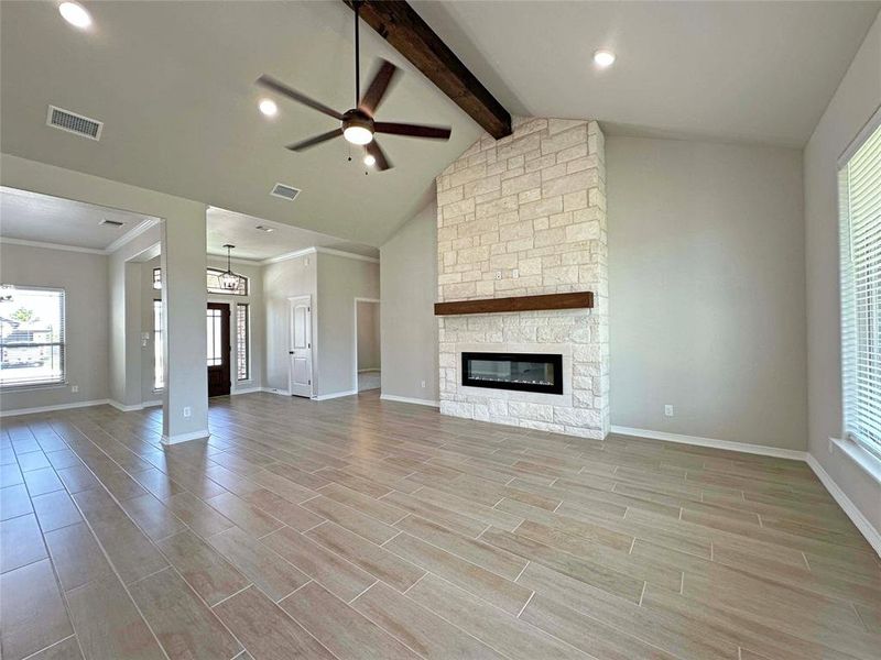 Unfurnished living room with ceiling fan, wood finish floors, a stone fireplace, beamed ceiling, and recessed lighting Unfurnished living room with ceiling fan, wood finish floors, a stone fireplace, beamed ceiling, and recessed lighting