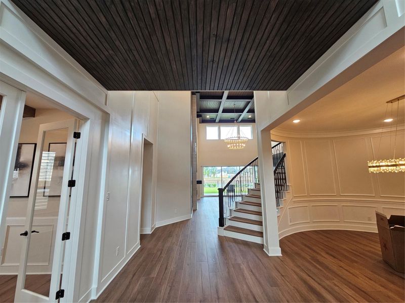 This stunning entryway features high ceilings, elegant lighting, and sleek wood flooring. The open staircase is complemented by custom wood paneling beneath, adding a unique touch. Double glass doors lead to an adjacent room, perfect for those seeking a stylish and inviting home. This stunning entryway features high ceilings, elegant lighting, and sleek wood flooring. The open staircase is complemented by custom wood paneling beneath, adding a unique touch. Double glass doors lead to an adjacent room, perfect for those seeking a stylish and inviting home.