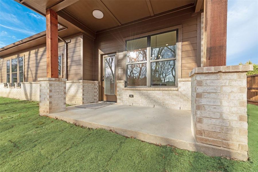 Rear Doorway to property with a patio area and a lawn