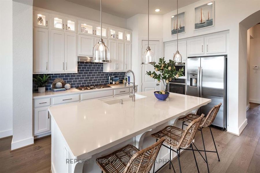 Kitchen with arched walkways, appliances with stainless steel finishes, dark wood finished floors, white cabinets, and recessed lighting Kitchen with arched walkways, appliances with stainless steel finishes, dark wood finished floors, white cabinets, and recessed lighting