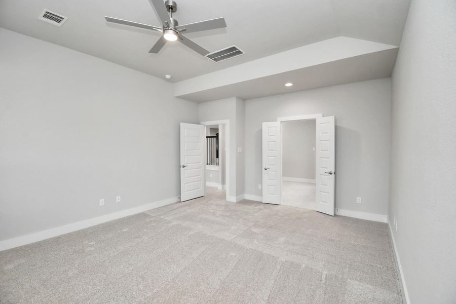 Retreat to the luxurious primary suite, your perfect escape for unwinding after a long day. Located on the first floor, this spacious room features plush carpeting, calming paint tones, high ceilings, and large windows with privacy blinds. Sample photo of completed home with similar floor plan. Actual colors and selections may vary.