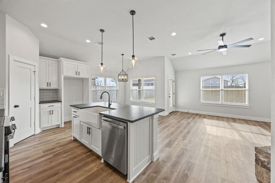 Kitchen featuring dark countertops, open floor plan, white cabinetry, recessed lighting, and vaulted ceiling