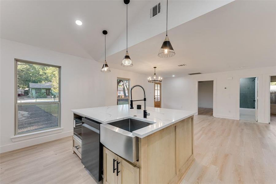 Kitchen featuring lofted ceiling, dishwasher, an island with sink, light hardwood / wood-style flooring, and sink