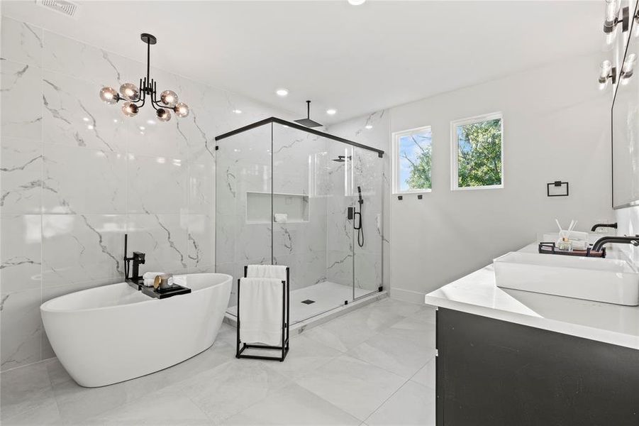Full bathroom featuring a marble finish shower, double vanity, marble finish floors, a soaking tub, and a chandelier