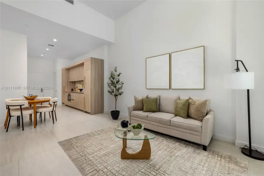 High ceilings featuring recessed lighting, large-format tile flooring, and custom cabinetry with built-in appliances