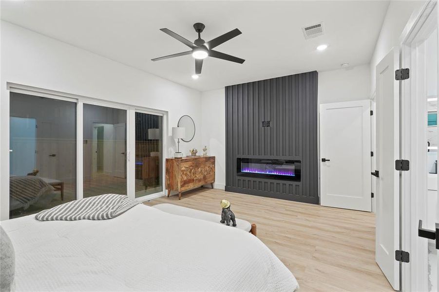 Bedroom featuring a glass covered fireplace, wood finished floors, a ceiling fan, recessed lighting, and access to outside Bedroom featuring a glass covered fireplace, wood finished floors, a ceiling fan, recessed lighting, and access to outside