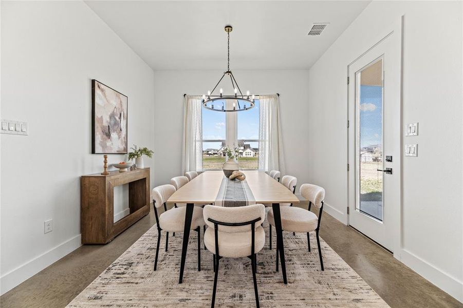 Dining room featuring a chandelier and concrete floors Dining room featuring a chandelier and concrete floors