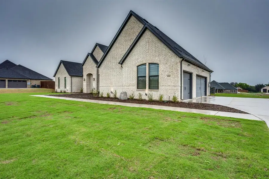 French provincial home featuring brick siding, a front lawn, a garage, and concrete driveway