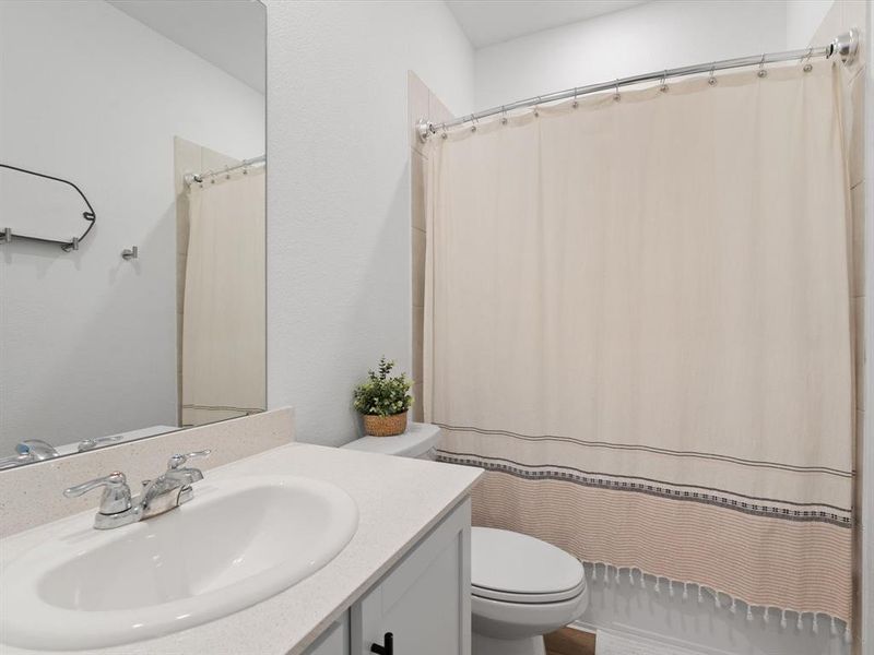 Bathroom featuring a shower with curtain, vanity, and toilet