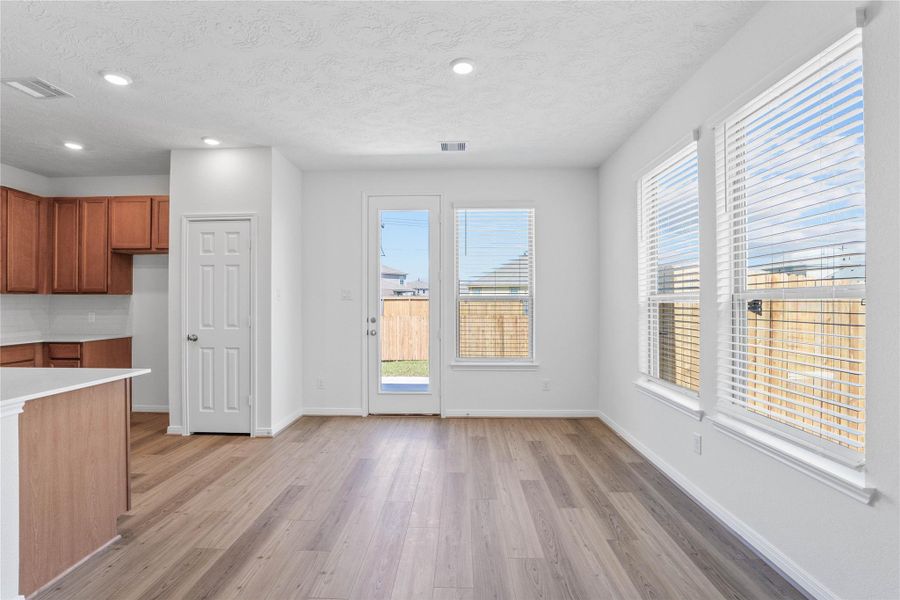 Start your day with a warm cup of coffee and quality time in this charming dining area! Highlights include large windows with blinds, custom neutral paint, vinyl plank flooring, recessed lighting, high ceilings, and a convenient door leading to the rear patio and backyard.