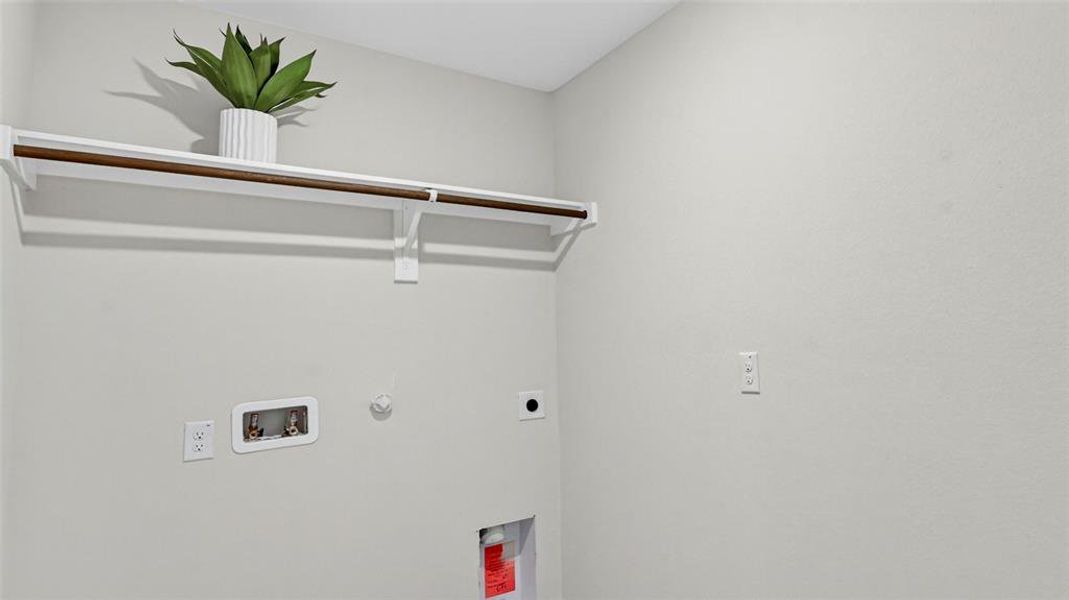 Utility area featuring a mounted shelf with a hanging rod, water hookups, and electrical outlets Utility area featuring a mounted shelf with a hanging rod, water hookups, and electrical outlets