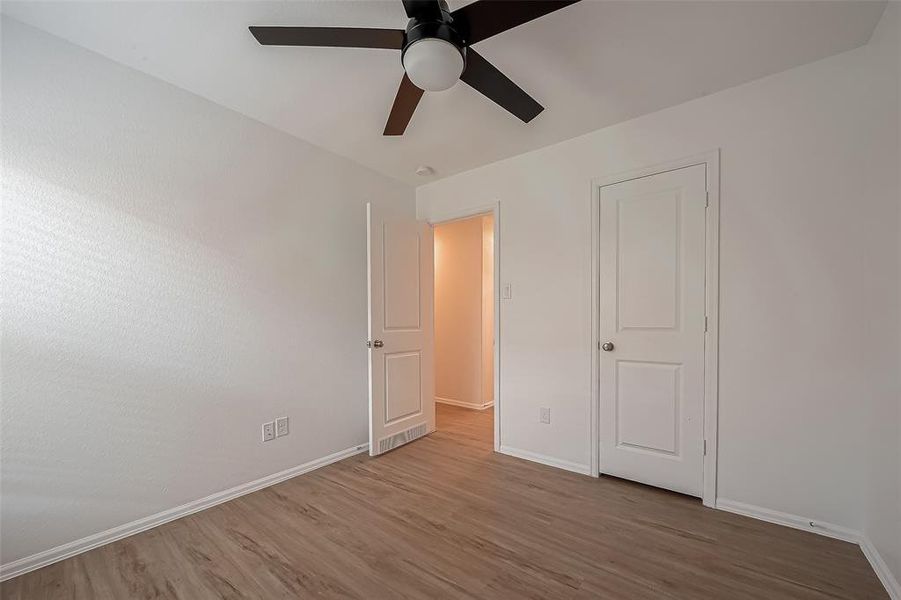 The first guest bedroom located off the hall at the front of the home, features a spacious closet and a ceiling fan for added comfort.