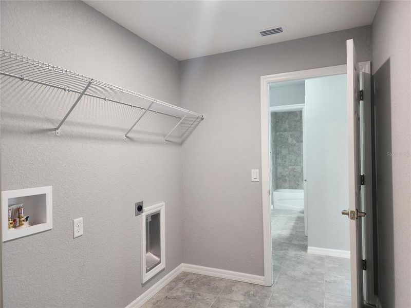 Laundry room off of the garage with washer and dryer hook-ups and shelving for storage