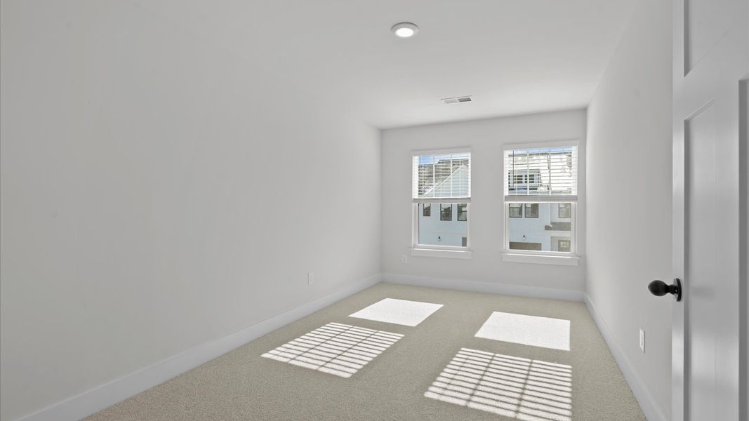 Elegant bedroom retreat featuring soft carpet and oversized windows that create a bright, welcoming space