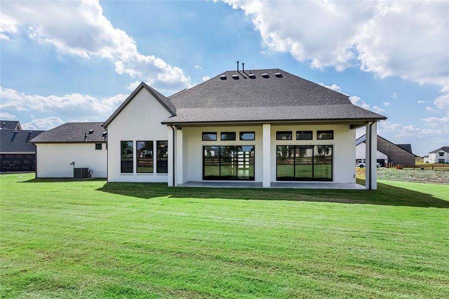 Back of property with a lawn, central air condition unit, and a patio area