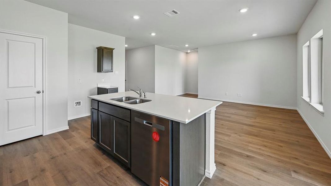 Kitchen featuring dishwasher, recessed lighting, a kitchen island with sink, dark wood finished floors, and dark brown cabinetry