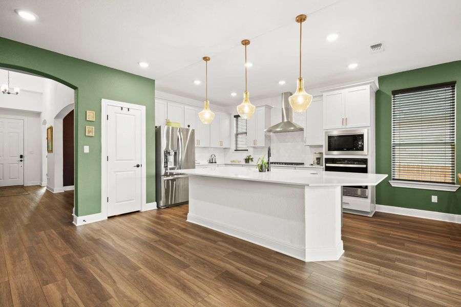 Kitchen with white cabinetry, a center island, appliances with stainless steel finishes, wall chimney range hood, and recessed lighting Kitchen with white cabinetry, a center island, appliances with stainless steel finishes, wall chimney range hood, and recessed lighting