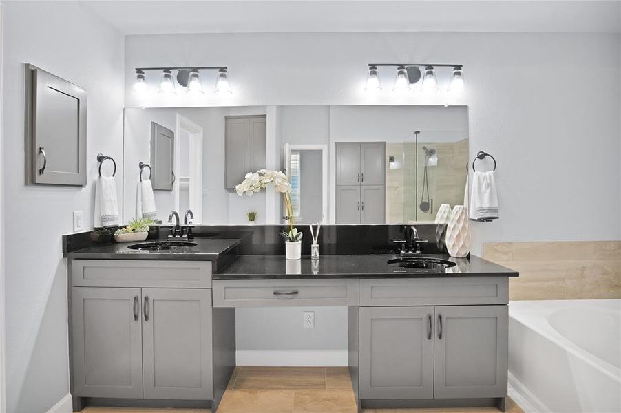 Primary bathroom with dual vanities, upscale fixtures and hardware, and beautiful tile patterned flooring.