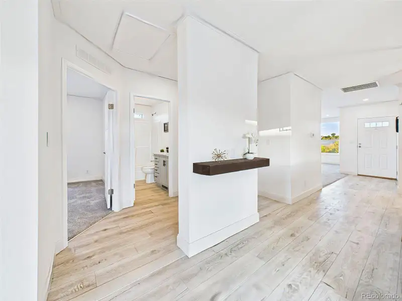 Open hallway with light wood flooring leading to guest rooms and bath. Open hallway with light wood flooring leading to guest rooms and bath.