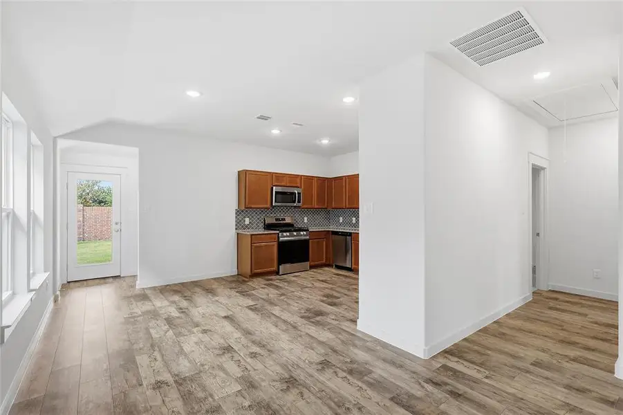 Kitchen featuring brown cabinets, appliances with stainless steel finishes, tasteful backsplash, light countertops, and light wood-style floors Kitchen featuring brown cabinets, appliances with stainless steel finishes, tasteful backsplash, light countertops, and light wood-style floors