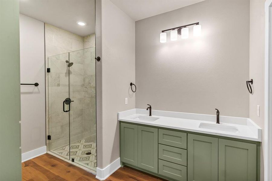 Bathroom featuring dark wood-type flooring, a shower stall, double vanity, and recessed lighting Bathroom featuring dark wood-type flooring, a shower stall, double vanity, and recessed lighting