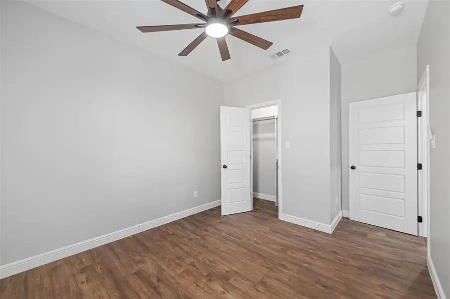 Unfurnished bedroom with ceiling fan, a spacious closet, a closet, and dark hardwood / wood-style flooring