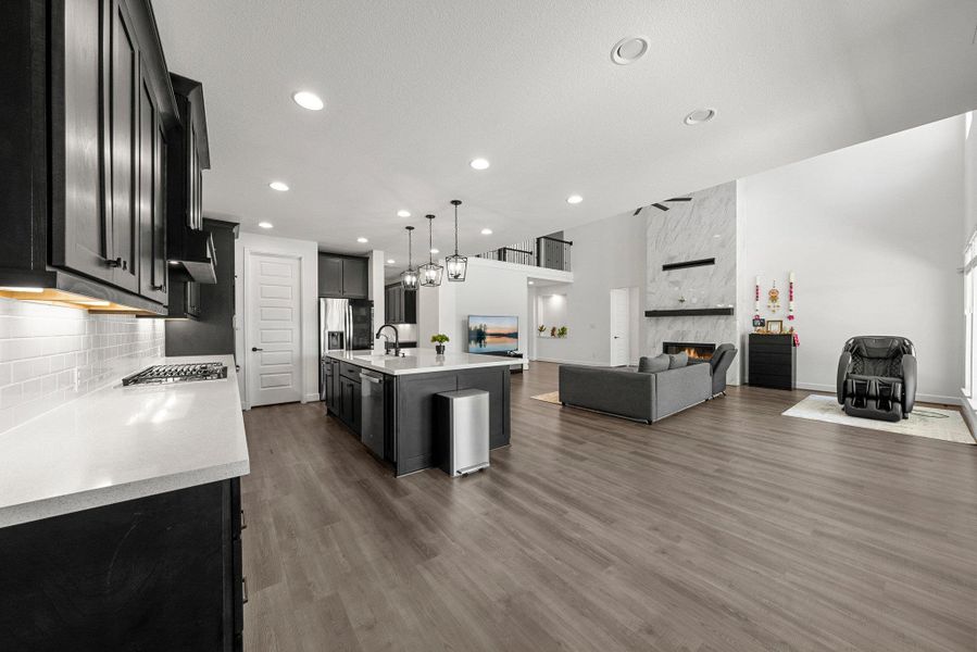 Kitchen with dark wood-type flooring, a premium fireplace, open floor plan, light countertops, and tasteful backsplash