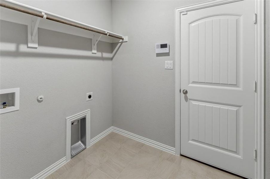 Utility area featuring light-toned tile flooring, light gray walls, and white baseboards