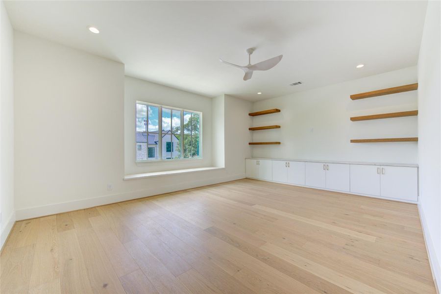 The spacious second-floor game room offers exceptional flexibility for entertainment, recreation, or casual family gatherings. Thoughtfully designed with custom built-in cabinetry, floating display shelves, and extensive storage, the space combines style with functionality. Large windows invite natural light while showcasing neighborhood views, and the continuous French Oak flooring enhances the room’s warm, sophisticated character. Whether envisioned as a media lounge, game room, study retreat, or secondar
