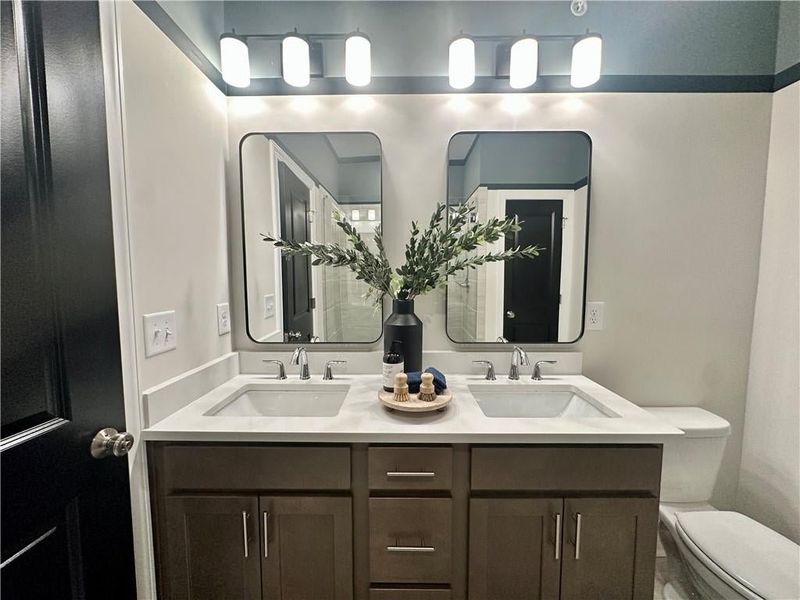 Owners Bathroom features quartz countertops, delta plumbing & Framed mirrors *Images shown are from a decorated model of the same floor plan. Design selections and color packages will vary by home.*