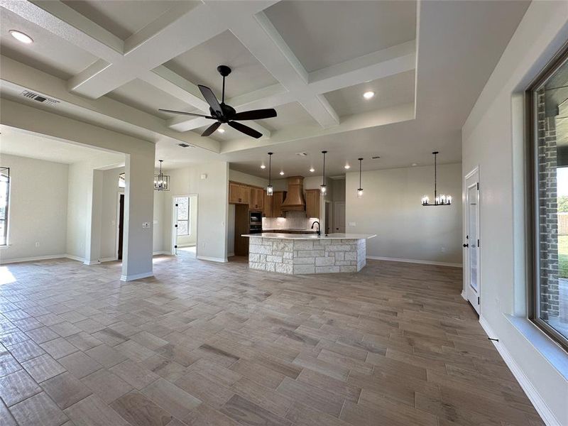 Unfurnished living room with a chandelier, recessed lighting, coffered ceiling, a ceiling fan, and beamed ceiling