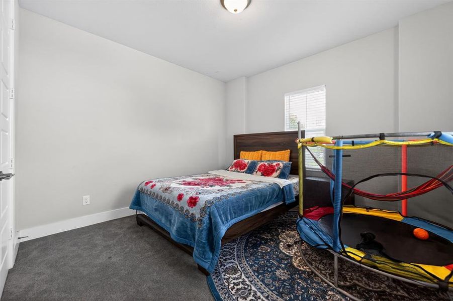 Bedroom featuring light-colored walls, carpeted flooring, and a window with blinds