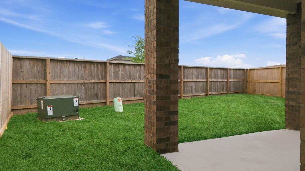 Outdoor covered patio with seating area overlooking a well-maintained lawn, perfect for relaxation.