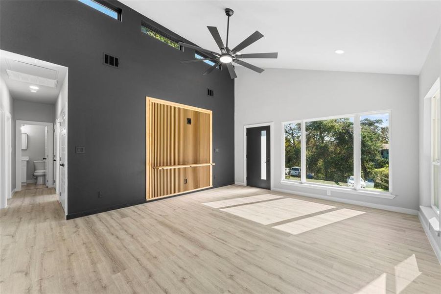 Unfurnished bedroom featuring light wood-style floors, high vaulted ceiling, and a ceiling fan