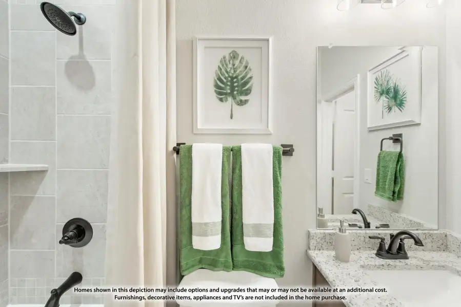 Bathroom with tiled walk-in shower, granite vanity, large mirror, and green towels on wall rack