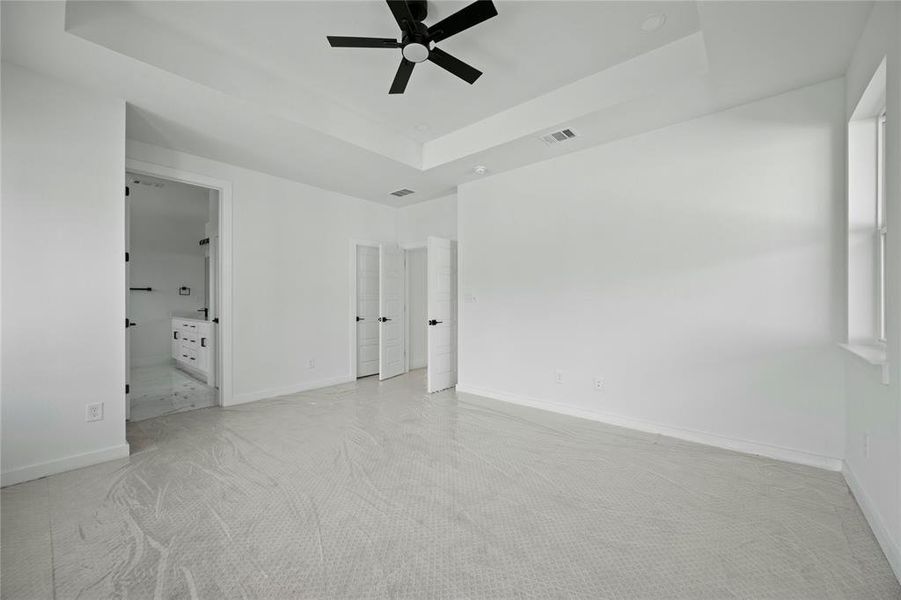 Spare room featuring ceiling fan, carpet floors, and a raised ceiling