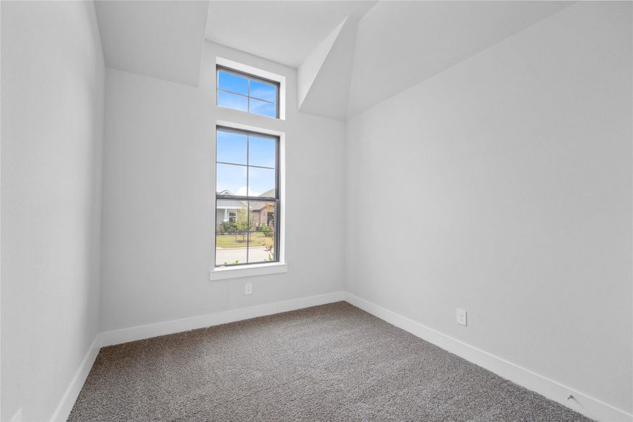 Tucked peacefully in the front of the home is this secondary bedroom. It features high sloped ceiling, custom paint, plush carpet, large windows, and an ample sized closet space!