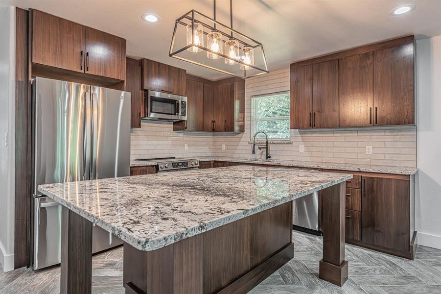 Kitchen with stainless steel appliances, light stone counters, dark brown cabinetry, decorative backsplash, and recessed lighting Kitchen with stainless steel appliances, light stone counters, dark brown cabinetry, decorative backsplash, and recessed lighting