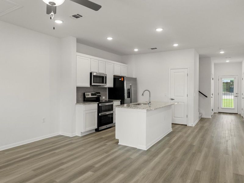 A well-appointed kitchen features a central island, modern appliances, and seamless flow into adjacent living spaces.