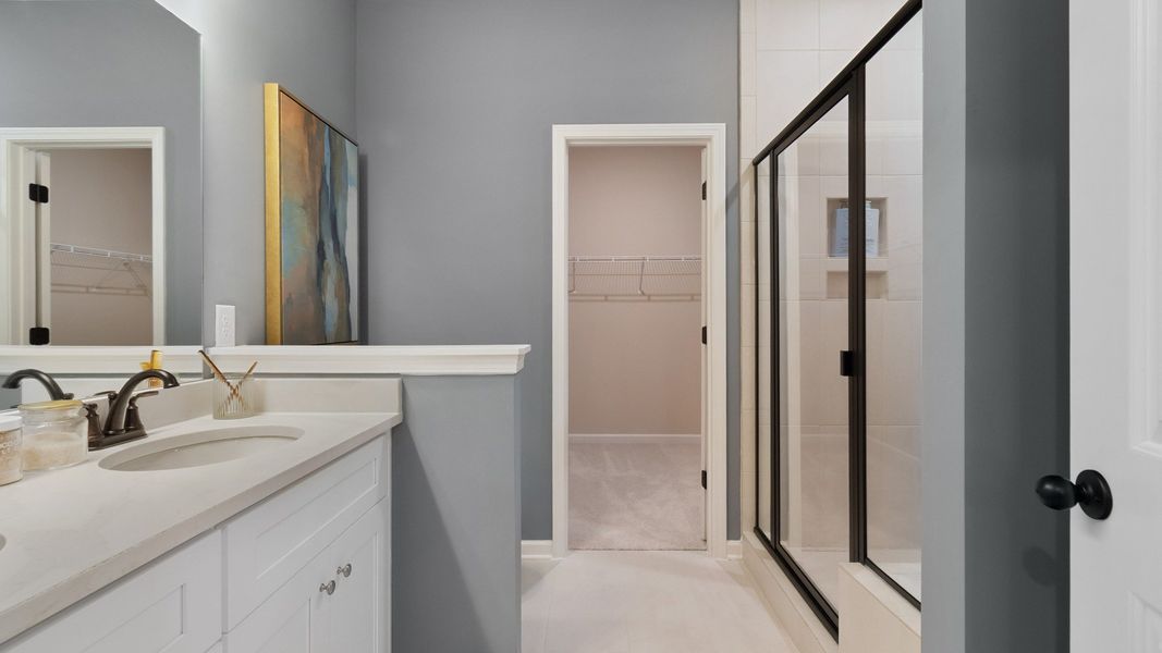 Luxurious primary bathroom with double vanities, quartz countertops, and separate walk-in shower.