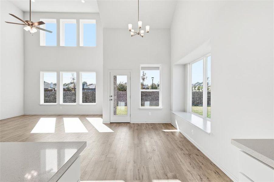 Foyer entrance featuring plenty of natural light, light wood finished floors, ceiling fan, a chandelier, and a towering ceiling