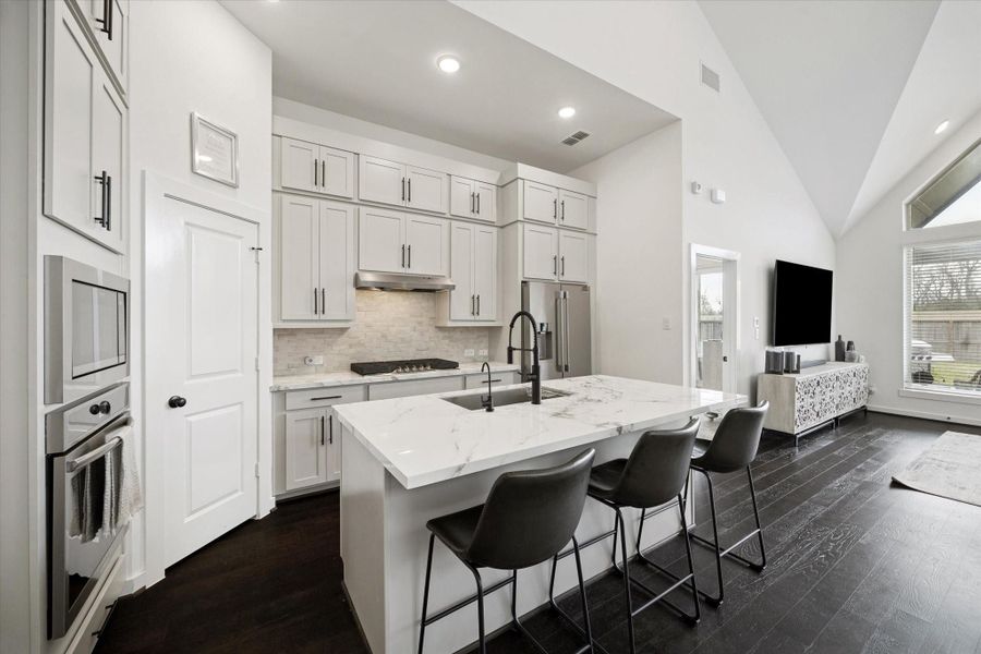 THE VIEW FROM THE KITCHEN ISLAND LOOKS TOWARD THE LIVING AREA, SHOWING THE DARK WOOD FLOORING THAT RUNS THROUGHOUT THE MAIN LEVEL.
