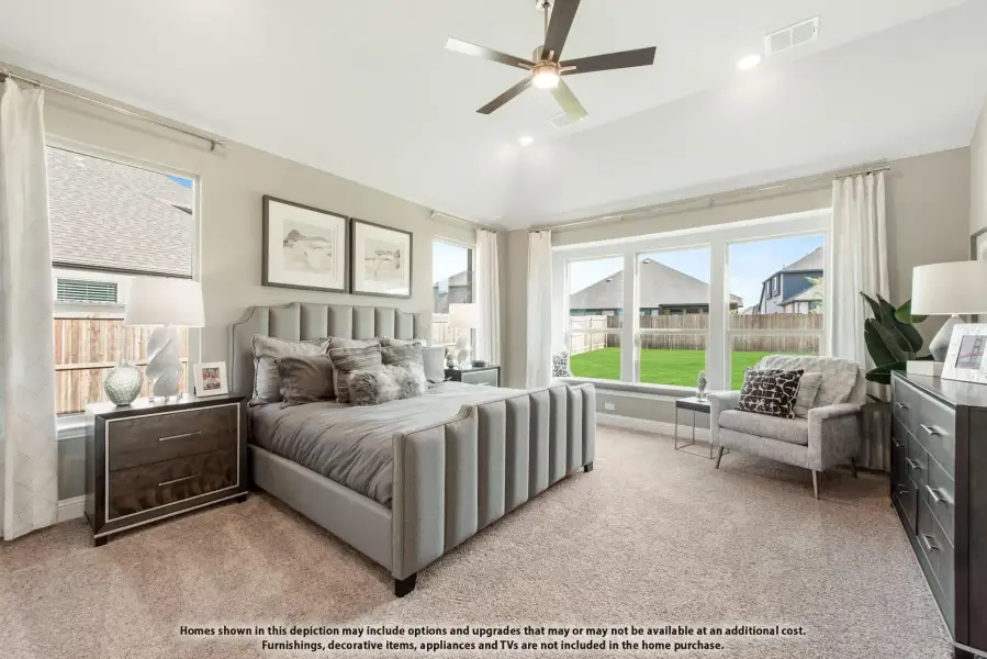 Master bedroom with upholstered bed, ceiling fan, carpet flooring, and large windows with backyard view