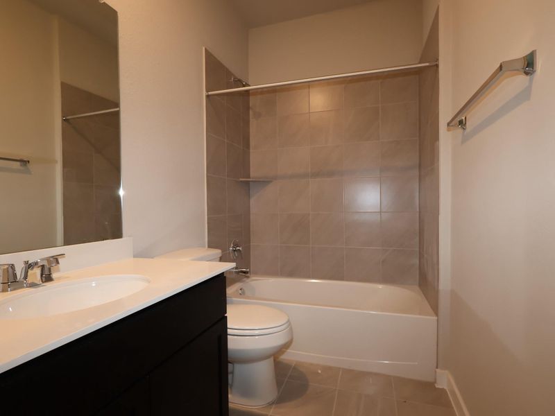 A pristine bathroom features a crisp white vanity, sleek mirror, and a combination shower-tub.